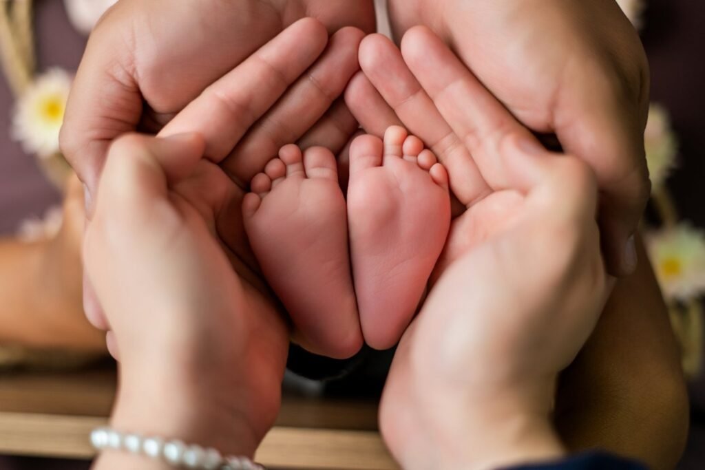 Pies de un recién nacido sostenidos entre las manos de sus padres