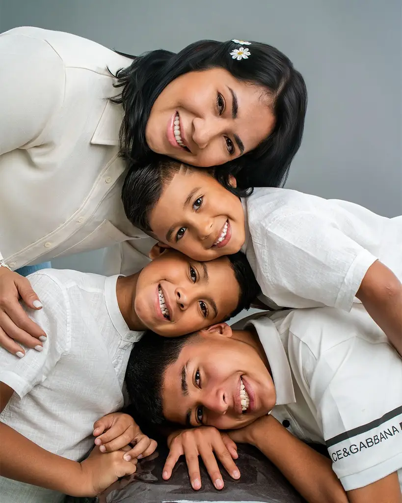 Mamá y sus tres hijos sonriendo en una sesión de fotos familiar en estudio en Quito